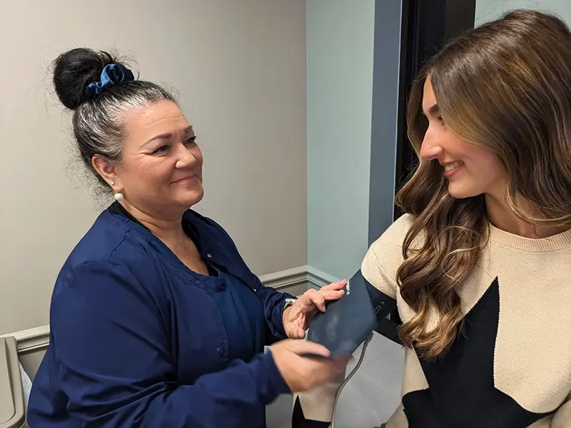 Happy Nurse Placeing Blood Pressure Cuff on Smiling Patient